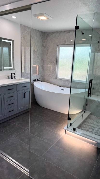 A remodeled bathroom with a freestanding tub, double vanity and glass shower